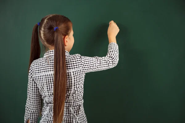 Schönes kleines Mädchen, das auf Tafel schreibt — Stockfoto