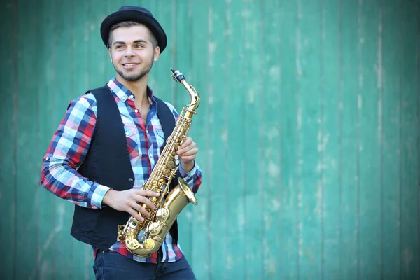 Young man playing on saxophone outside near the old wall — Stock Photo, Image