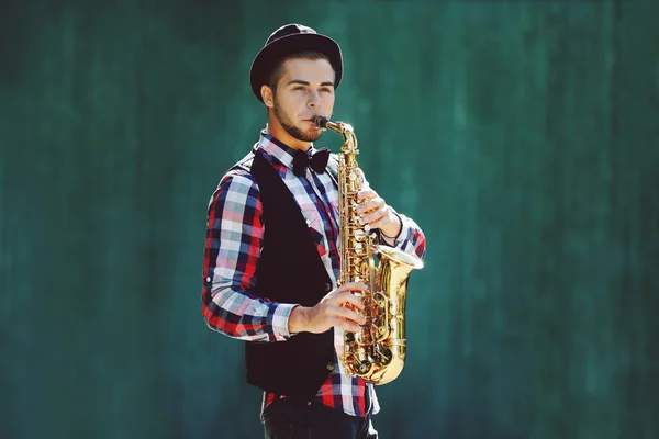 Jeune homme jouant sur le saxophone à l'extérieur près du vieux mur — Photo