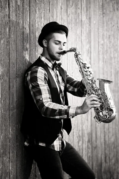 Jovem tocando saxofone fora perto da parede velha — Fotografia de Stock