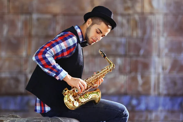 Hombre con saxofón afuera cerca de la pared de ladrillo —  Fotos de Stock