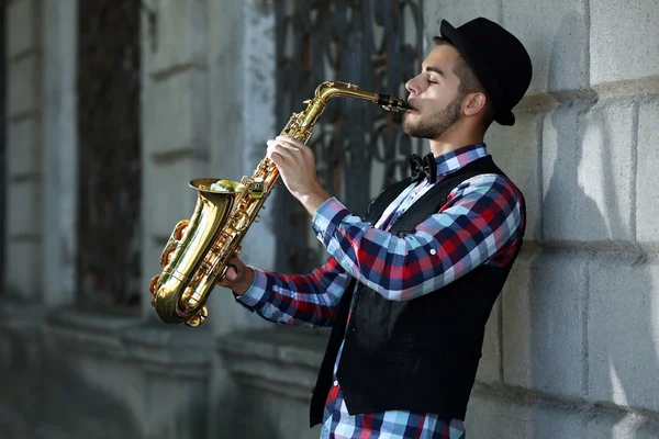 Człowiek z saksofon poza w pobliżu mur z cegły — Zdjęcie stockowe