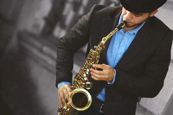 Muž s saxofon mimo u cihlové zdi — Stock fotografie
