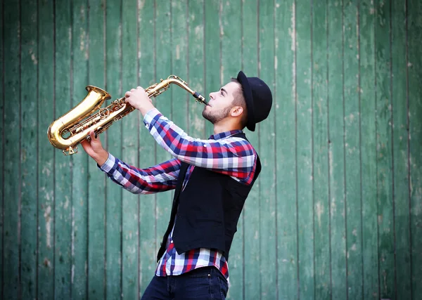 Muzyk gra saksofon na zielonym tle drewniane — Zdjęcie stockowe