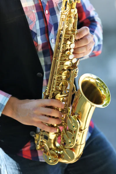 Joven guapo toca el saxo al aire libre, de cerca — Foto de Stock