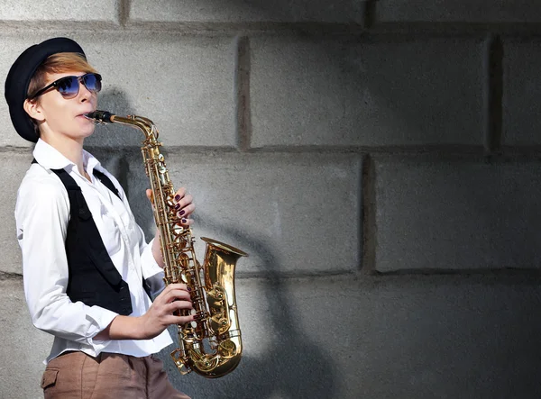 Mujer atractiva en sombrero toca saxofón — Foto de Stock