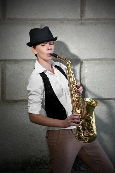 Atrakcyjna kobieta w kapeluszu gra saksofon — Zdjęcie stockowe