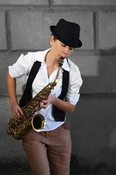 Привлекательная женщина в шляпе играет на саксофоне — стоковое фото