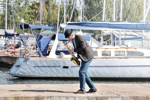 Stilig man spelar sax framför yacht — Stockfoto
