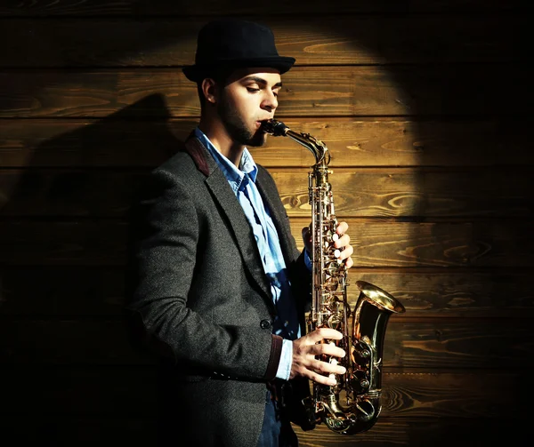 Elegante saxofonista toca jazz em fundo de madeira — Fotografia de Stock