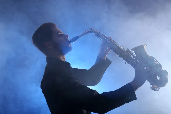 Elegante saxofonista toca jazz en humo azul —  Fotos de Stock