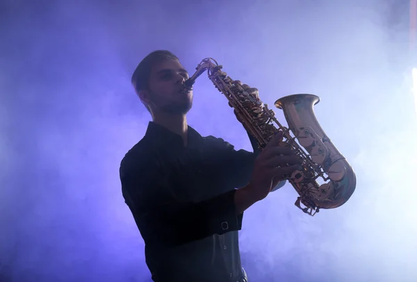 Elegant saxophonist plays jazz  in blue smoke — Stock Photo, Image