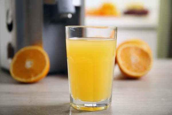 Odšťavňovač a pomerančový džus na kuchyňském stole — Stock fotografie