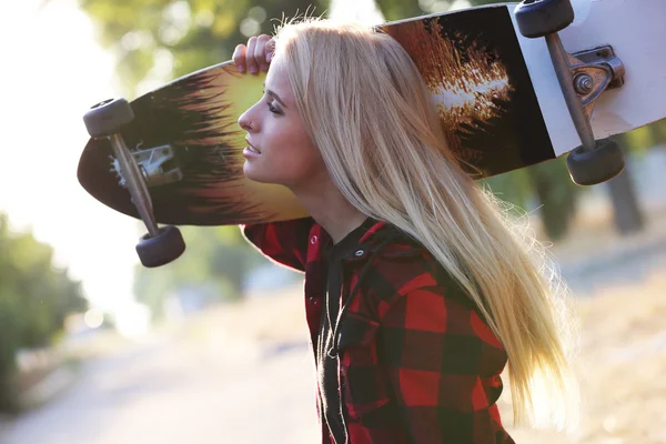 Mulher com placa de patinação — Fotografia de Stock