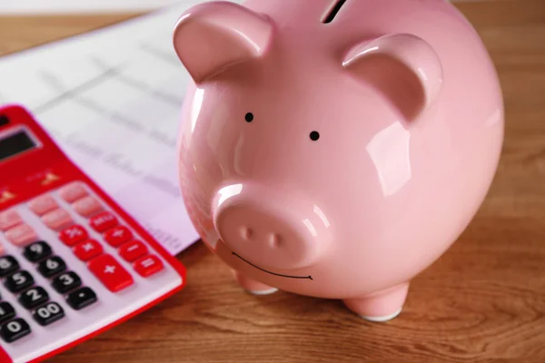 Pig moneybox and calculating equipment on desk closeup — Stock Photo, Image