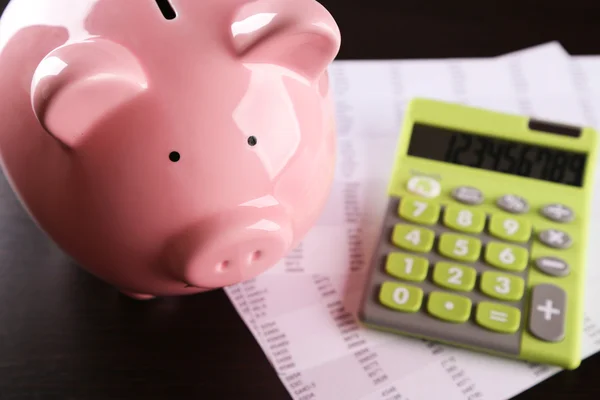 Pig moneybox and calculating equipment on desk closeup — Stock Photo, Image