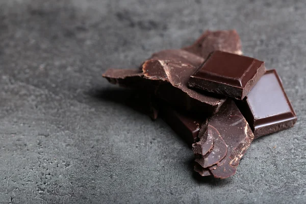 Pedaços de chocolate escuro no fundo cinza escuro — Fotografia de Stock