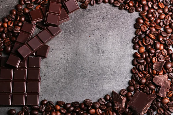 Piezas de chocolate negro y granos de café sobre fondo gris oscuro — Foto de Stock