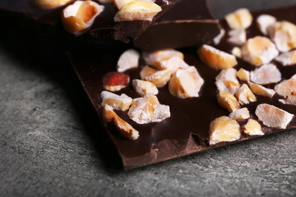 Czarne kawałki czekolady i orzechów na ciemnoszarym tle — Zdjęcie stockowe