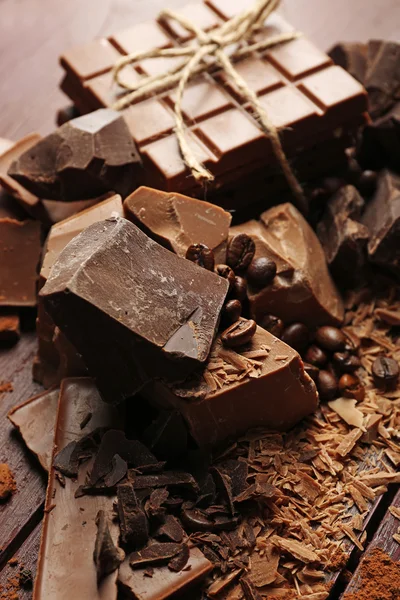 Разнообразие кусочков шоколада, зерна кофе и какао порошок на деревянном фоне — стоковое фото