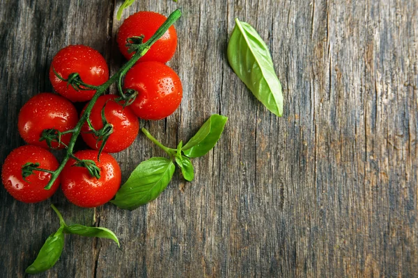 Cherry tomatoes with basil on wooden table close up — Stock Photo, Image