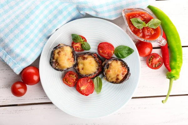 Plato de berenjena con tomates cherry y queso en plato blanco sobre mesa de madera, vista superior —  Fotos de Stock