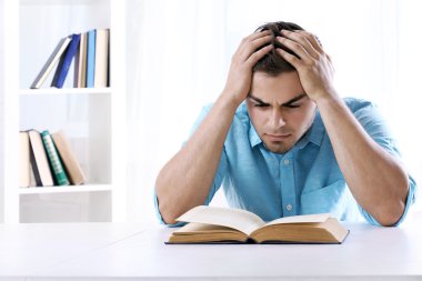Genç adam masada kitap okumak