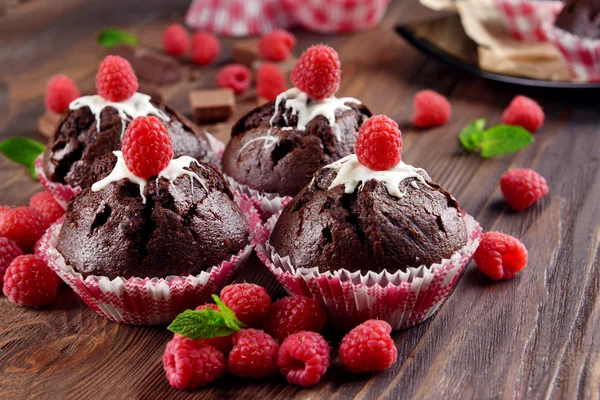 Deliciosos cupcakes de chocolate con bayas y menta fresca en la mesa de madera de cerca — Foto de Stock