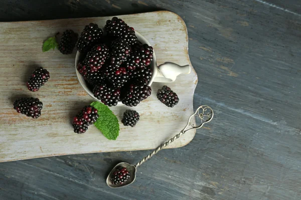 Montón de moras dulces con menta en taza en la mesa de cerca — Foto de Stock