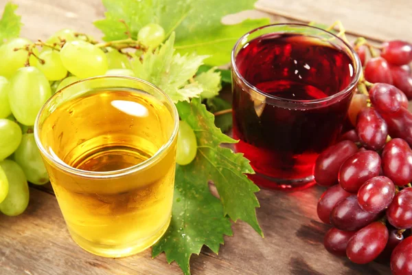 Glasses of grape juice on wooden table, closeup — Stock Photo, Image