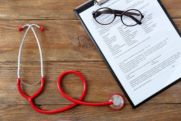 Estetoscopio médico con portapapeles en mesa de madera de cerca —  Fotos de Stock