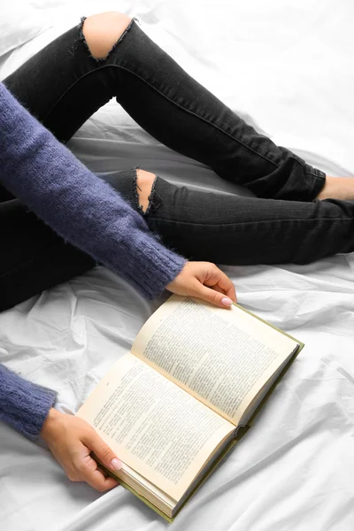 Vrouw in zwarte jeans lezen boek op bed bovenaanzicht punt — Stockfoto