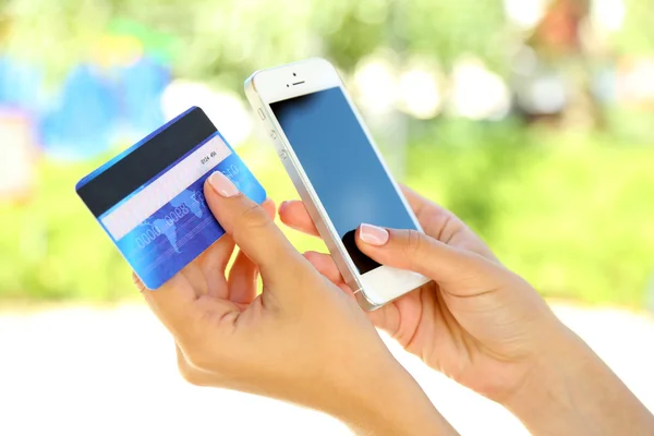 Cep telefonu ve kredi kartı açık havada, kadının elinde kapat — Stok fotoğraf