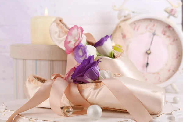 Beautiful composition of decorated ballet shoes with old clocks on creamy wooden  background — Stock Photo, Image