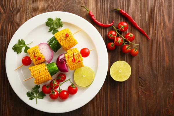 Pyszne kukurydza z grilla i warzyw na talerzu biały na tle drewniane — Zdjęcie stockowe