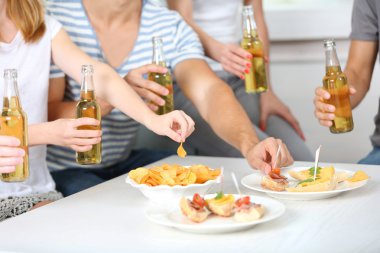 Arkadaşlar el ile şişe bira ve aperatifler, yakın çekim