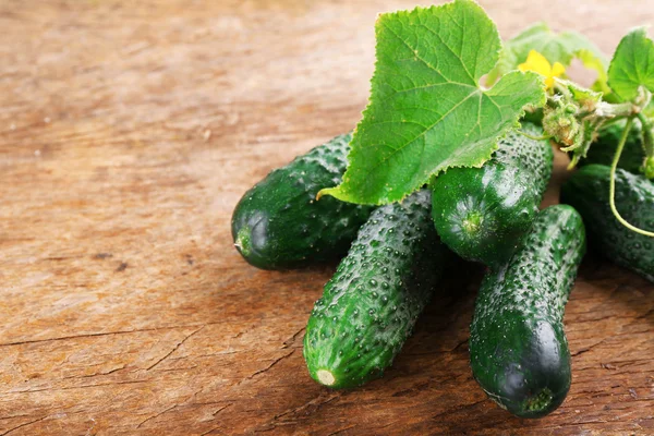 Komkommers met bladeren op houten achtergrond — Stockfoto