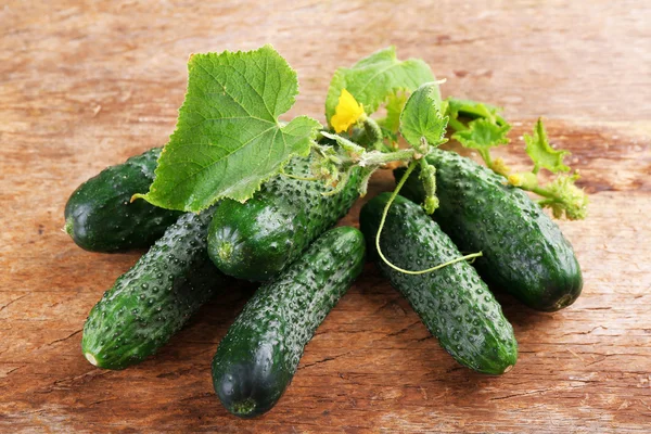 Komkommers met bladeren op houten achtergrond — Stockfoto