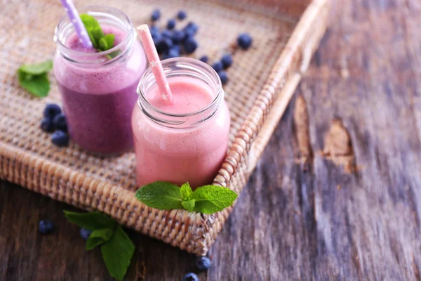 Čerstvé jahody a borůvky jogurt na proutěné, dřevěné pozadí — Stock fotografie
