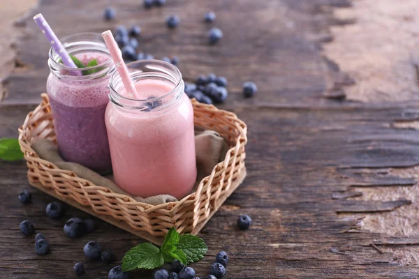 Fresh strawberry and blueberry yogurt on wicker against wooden background — Stock Photo, Image