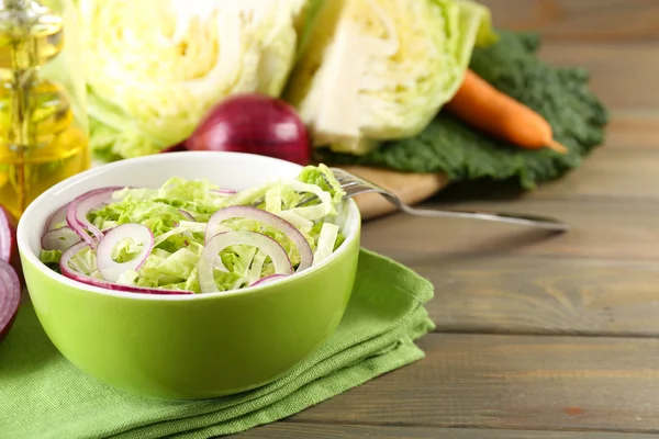 Savojen kål och lök sallad serveras i skål på träbord — Stockfoto