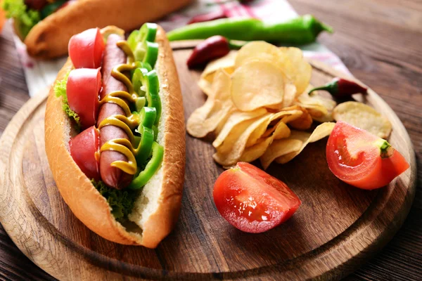 Hot dog et légumes sur planche à découper en bois — Photo