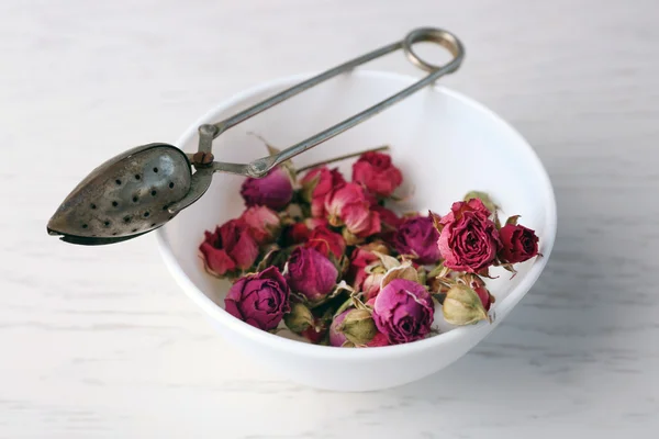 Tea rose in bowl on light wooden background — Stock Photo, Image