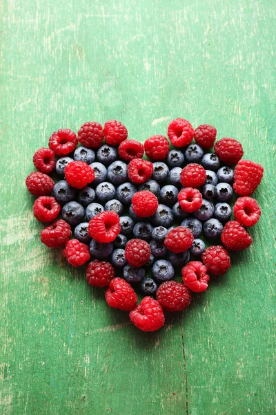 Herzförmige Himbeeren und Blaubeeren auf altem Holzgrund — Stockfoto