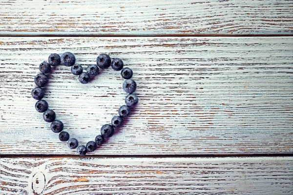 Czarne jagody na stare drewniane tła w kształcie serca — Zdjęcie stockowe
