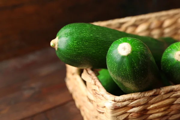 Fresh zucchini in wicker basket on wooden background — Stock Photo, Image