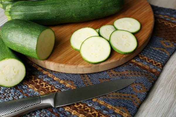 Calabacín fresco en rodajas sobre tabla de cortar, sobre fondo de madera —  Fotos de Stock