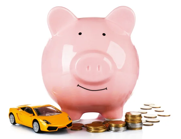 Piggy bank with car toy and coins around, isolated on white — Stock Photo, Image