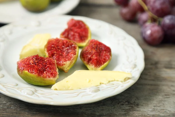 Reife Feigen und Käse auf Teller, auf Holzgrund — Stockfoto