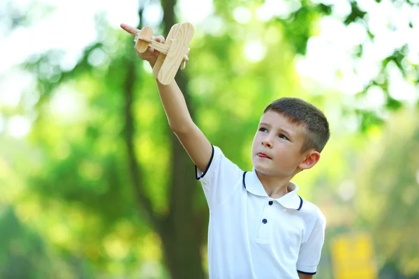 Little boy plays with wooden plane — Stock Photo, Image